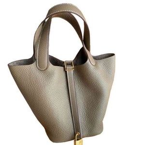 Taupe leather bucket handbag with gold hardware. Four feet on bottom